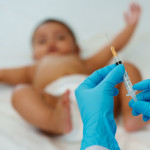 Doctor holding syringe and preparing vaccine giving injection to baby