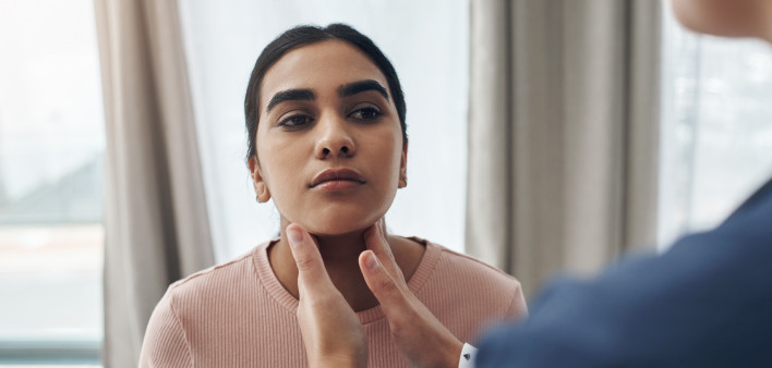 doctor checking patient’s throid gland,
