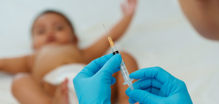 Doctor holding syringe and preparing vaccine giving injection to baby