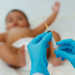 Doctor holding syringe and preparing vaccine giving injection to baby