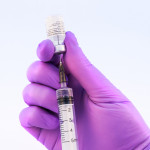 Doctor using Pfizer-BioNTech Covid-19 vaccine on a white background.