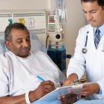 Doctor Explaining Consent Form To Senior Patient Writing