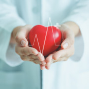 Female medical doctor holding red heart shape in hand with graphic of heart beat, cardiology and insurance concept