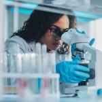 Medical Science Laboratory: Portrait of Beautiful Black Scientist Looking Under Microscope