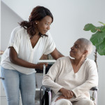 A young woman pushes her mother in a wheelchair through the house as she comes to help and support through her Cancer journey.