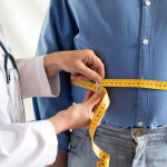 doctor measuring mans stomach
