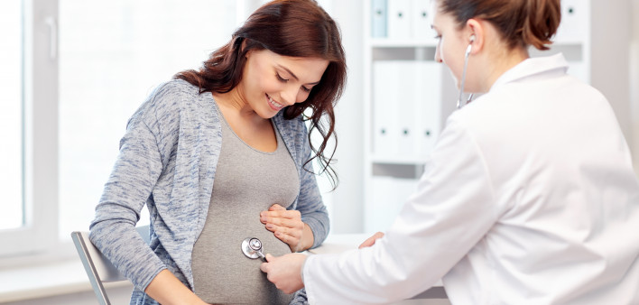 pregnancy, gynecology, medicine, health care and people concept - gynecologist doctor with stethoscope listening to pregnant woman baby heartbeat