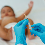 Doctor holding syringe and preparing vaccine giving injection to baby
