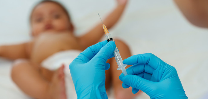 Doctor holding syringe and preparing vaccine giving injection to baby