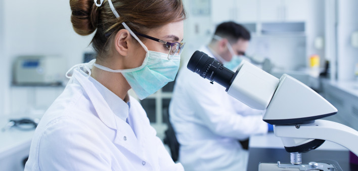 Team of experienced biologists working on microscopes in laboratory