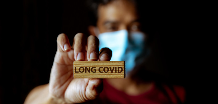 Masked Asian man show wooden sign with wording "Long Covid"
