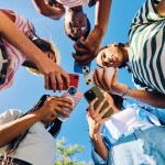 group of teens in circle all looking at phones