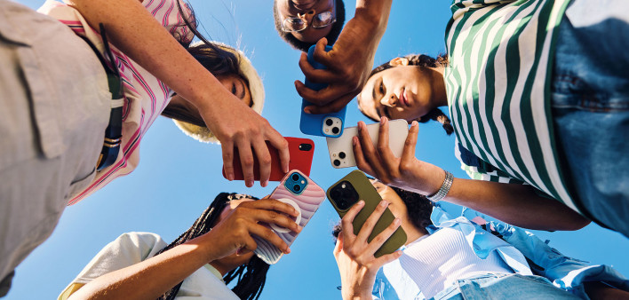 group of teens in circle all looking at phones
