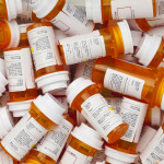 Dozens of prescription medicine bottles in a jumble. This collection of pill bottles is symbolic of the many medications senior adults and chronically ill people take.