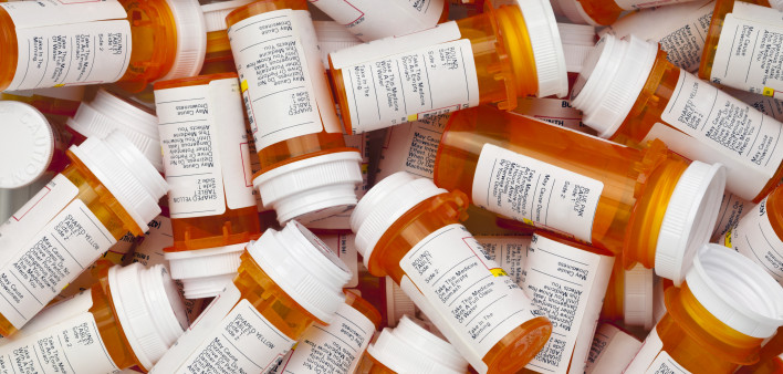 Dozens of prescription medicine bottles in a jumble. This collection of pill bottles is symbolic of the many medications senior adults and chronically ill people take.