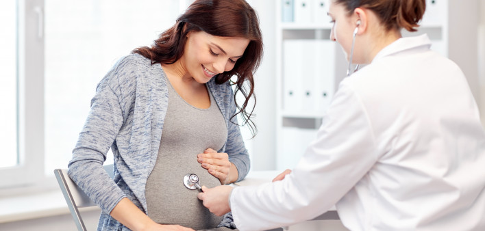 pregnancy, gynecology, medicine, health care and people concept - gynecologist doctor with stethoscope listening to pregnant woman baby heartbeat