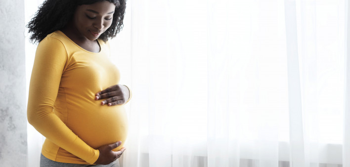 Beautiful pregnant african woman hugging her tummy