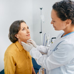 doctor checking a patients thyroid