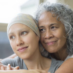 Ethnic young adult female cancer patient hugged by her mother