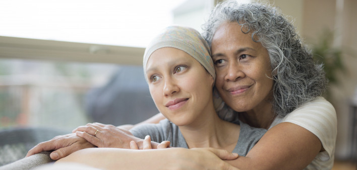 Ethnic young adult female cancer patient hugged by her mother