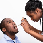 black man getting his throat checked by female nurse doctor