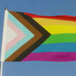 Inclusive LGBTQI+ Pride Flag Fluttering against a blue sky