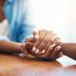Closeup shot of two unrecognizable people holding hands in comfort at home