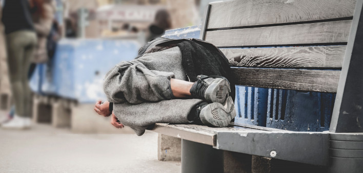 homeless man asleep on bench