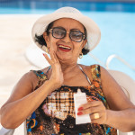 Mature woman applying suntan lotion sunscreen beach
