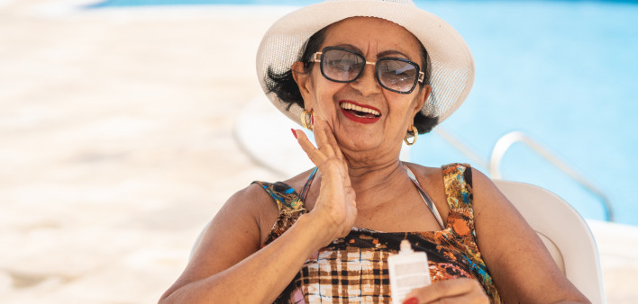 Mature woman applying suntan lotion sunscreen beach