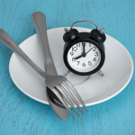 alarm clock on plate with fork and knife fastting diet