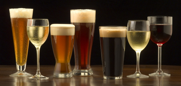 An assortment of glasses of wine and beer including a classic pilsner flute, a sparkling wine glass, an American half pint glass, a weizen or wheat beer glass, an American pint glass, a white wine glass, and a red wine glass.