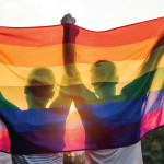 Silhouette of guys holding up pride flag gay