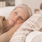 Tired woman after cancer treatment lying on couch at home