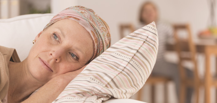 Tired woman after cancer treatment lying on couch at home