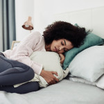 Cropped shot of an attractive young woman lying down on her bed and suffering from period pains at home