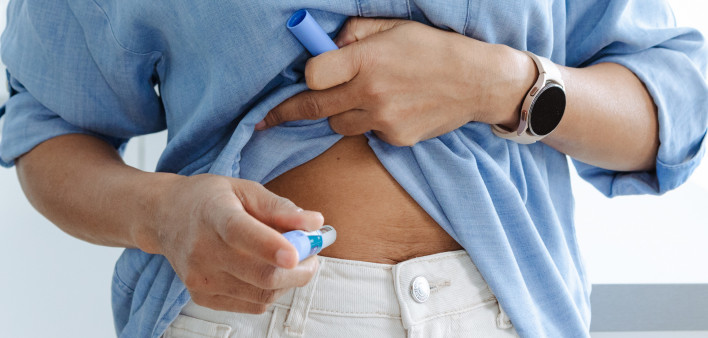 A woman self-administering medicine with a pen injector