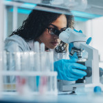 Medical Science Laboratory: Portrait of Beautiful Black Scientist Looking Under Microscope