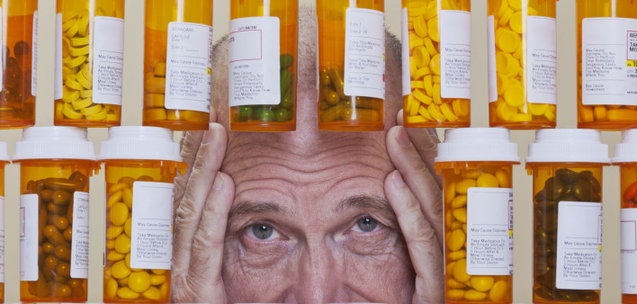 Depressed Senior Man Looking Through Rows of Prescription Medication