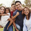 Three generation Hispanic family standing in the park, smiling