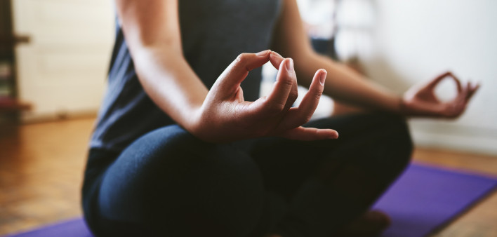 Cropped shot of an unrecognizable woman sitting on a yoga mat and meditating alone in her home