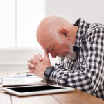 Worried senior man using laptop at home.