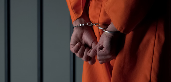 Prisoner with handcuffed arms behind back, another jail transfer, criminal