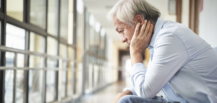 senior asian patient sitting in hospital hallway looking sad and depressed