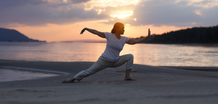 Woman doing Tai Chi chuan at sunset on the beach. solo outdoor activities. Social Distancing. Healthy lifestyle