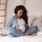young pretty african american woman pregnant laying in bed