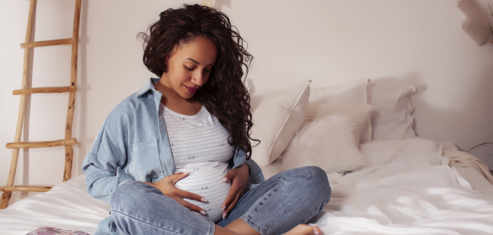 young pretty african american woman pregnant laying in bed