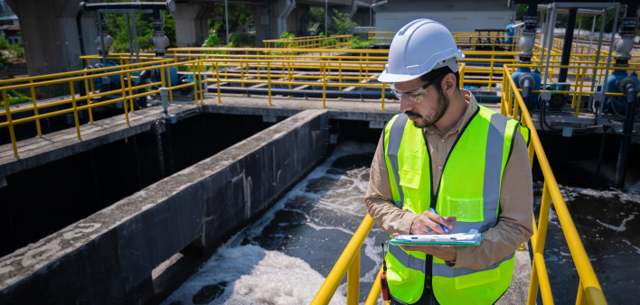 Engineer take water from wastewater treatment pond to check the quality of the water. After going through the wastewater treatment process