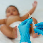 Doctor holding syringe and preparing vaccine giving injection to baby