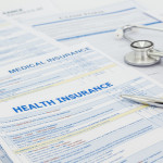 Medical insurance application, silver pen and stethoscope. Legal law contract and health insurance concepts.